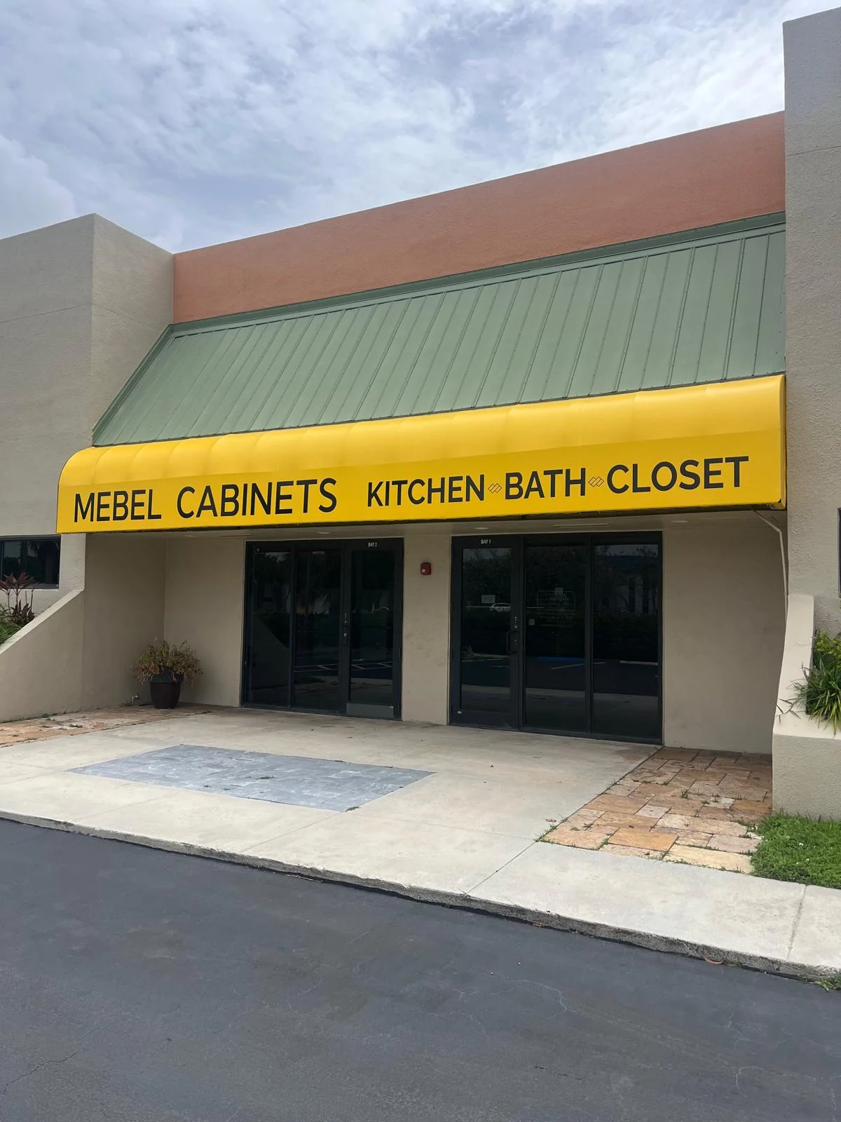 Angled view of the MEBEL CABINETS showroom and yellow awning in Pompano Beach